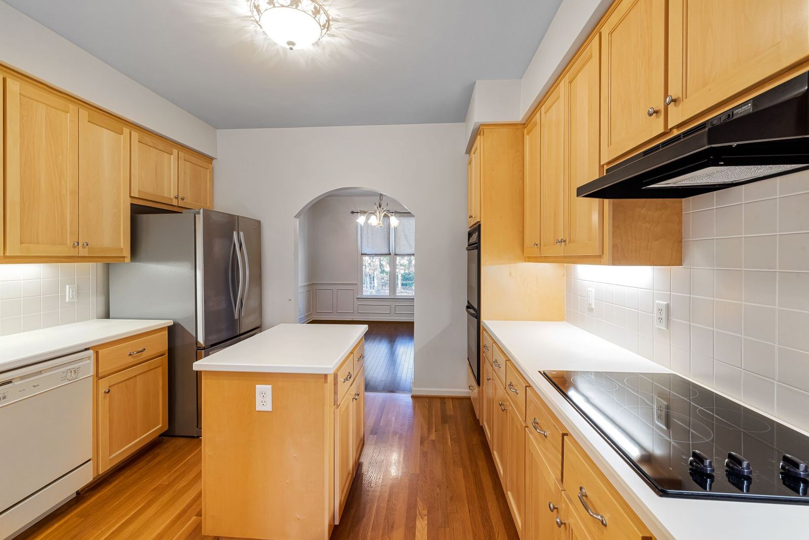 Kitchen with light wood cabinets, a center island, and a wood floor