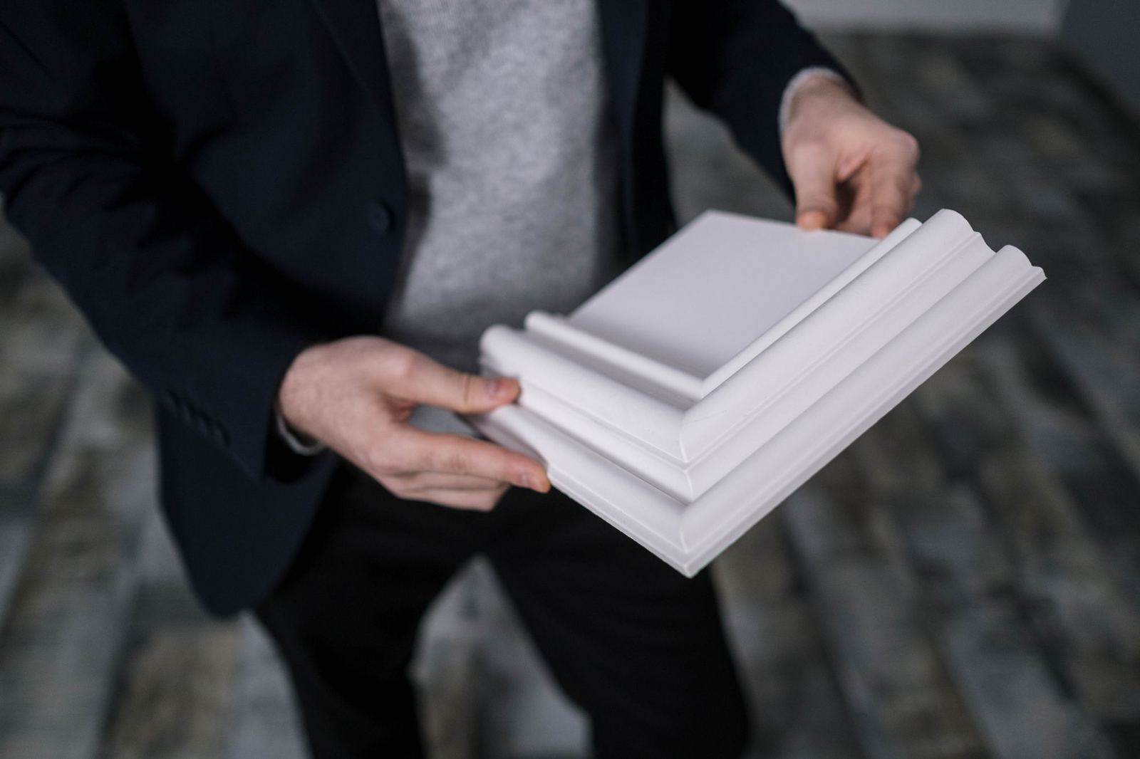 Hands holding white crown molding profile samples