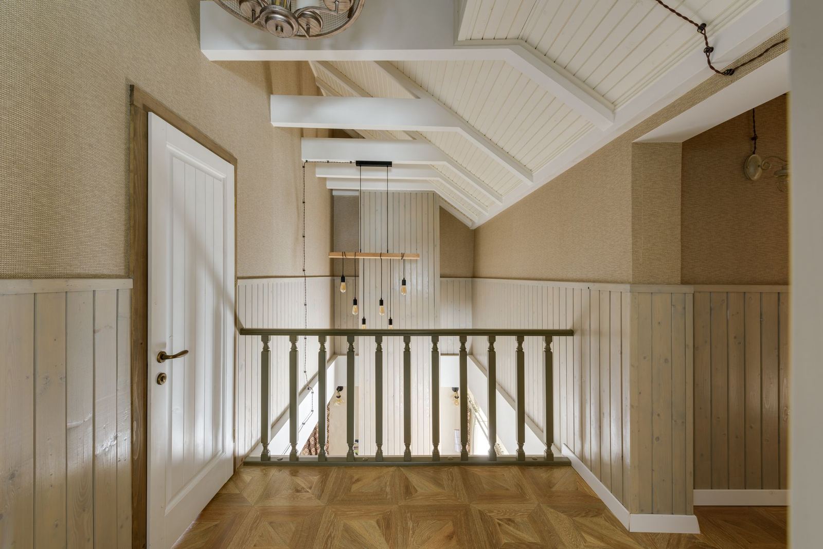 Upstairs hall with painted wood wainscoting, baseboard, a cased white door, and a wood railing
